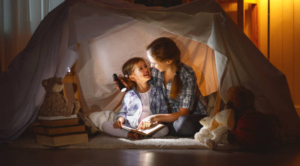 istock mother and child daughter with a book and a flashlight before going to bed 666315224