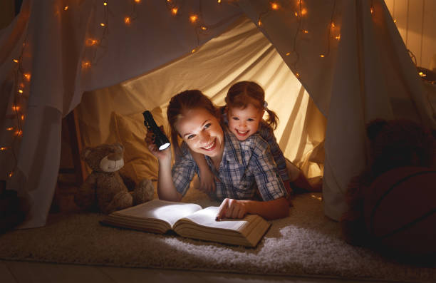 istock mother and child daughter with a book and a flashlight before going to bed 666318630