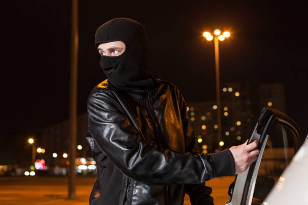 istock Male thief with balaclava on head opening car door 666335524