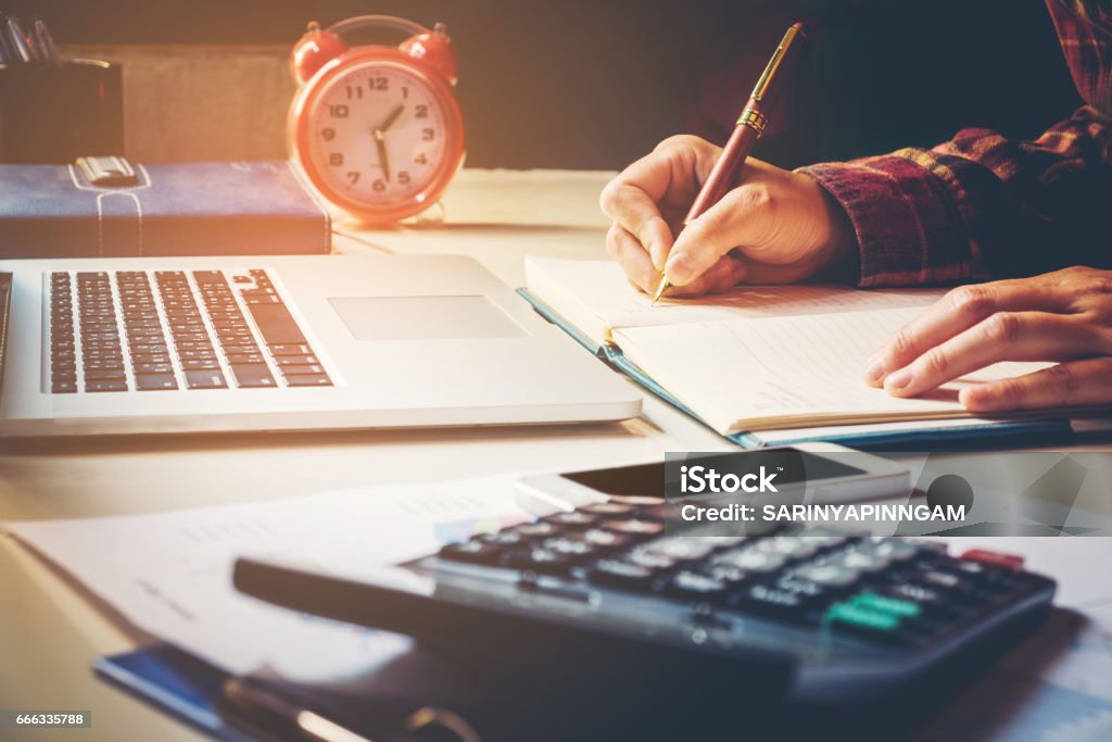 Businessman calculator at the office Financial data analyzing hand writing and counting on calculator on wood desk Businessman calculator at the office Financial data analyzing hand writing and counting on calculator Learning Stock Photo