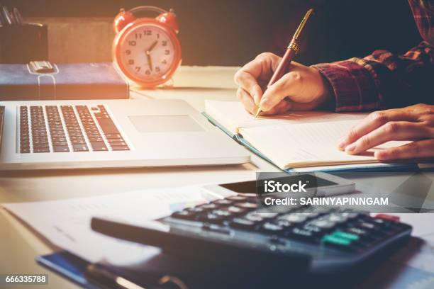 Businessman Calculator At The Office Financial Data Analyzing Hand Writing And Counting On Calculator On Wood Desk Stock Photo - Download Image Now