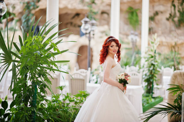 noiva red-haired charming com o ramalhete do casamento na mão posed no grande salão do casamento - loose hair - fotografias e filmes do acervo