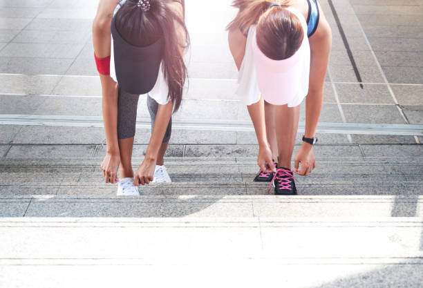 Young sport women tying up running shoe on stairs in city scape with flare light, getting ready for jogging. Young sport women tying up running shoe on stairs in city scape with flare light, getting ready for jogging. Activewear leggings and shoes. slenderman fictional character stock pictures, royalty-free photos & images