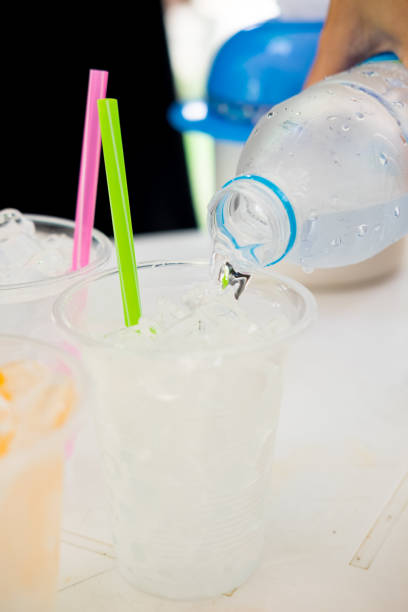 pouring water many transparent plastic cups with straw