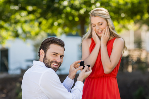 Man proposing a woman with a ring on his knee in the restaurant