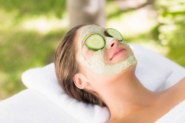 Attractive woman having cucumber on her face at spa center