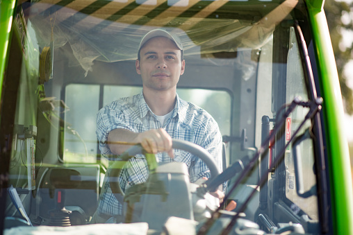 Smiling farmer driving an harvesting machine