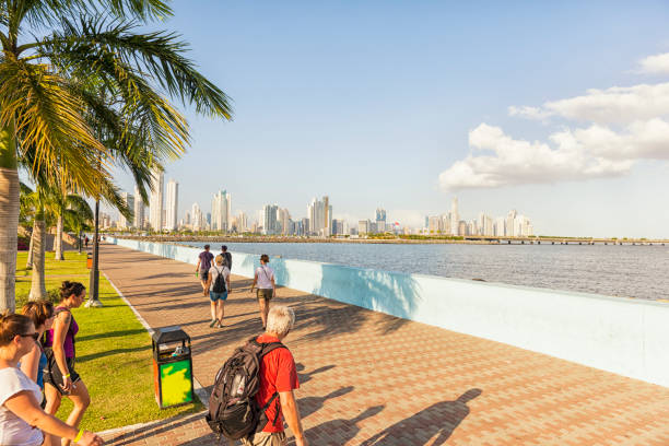 Tourists in Panama city Group of tourist on the pedestrian sidewalk along panoramic path to the centre of Panama city. In distance high buildings, skyline, bridge against blue sky. panama city panama stock pictures, royalty-free photos & images