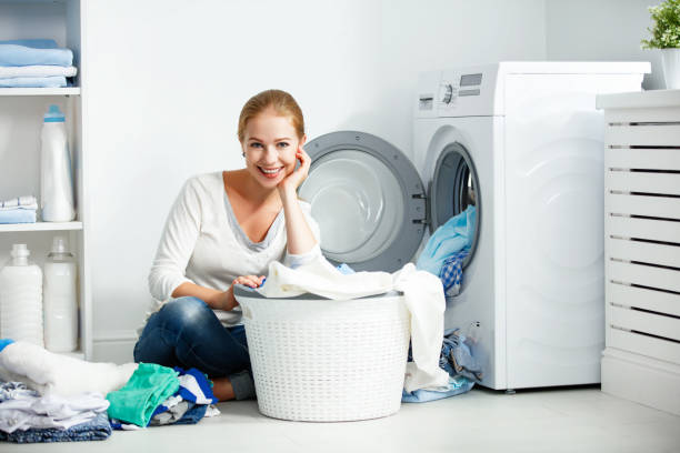 donna felice casalinga nella lavanderia vicino alla lavatrice con vestiti sporchi - 5412 foto e immagini stock