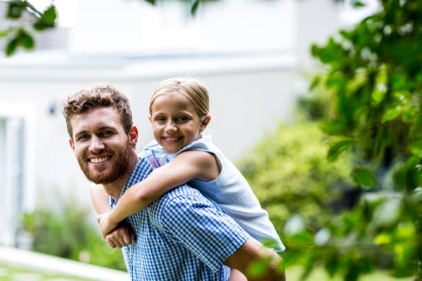 istock Smiling father carrying daughter in yard 666386444