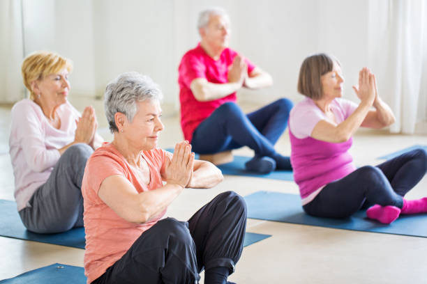 istock Senior friends with hands joined meditating in gym 666386538