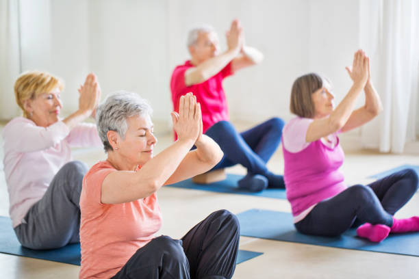 istock Senior friends with hands joined meditating in gym 666386546