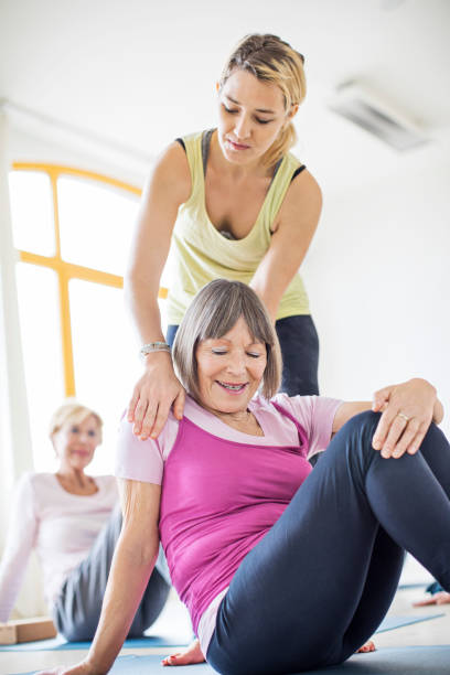 istock Instructor assisting senior woman in doing yoga 666387132
