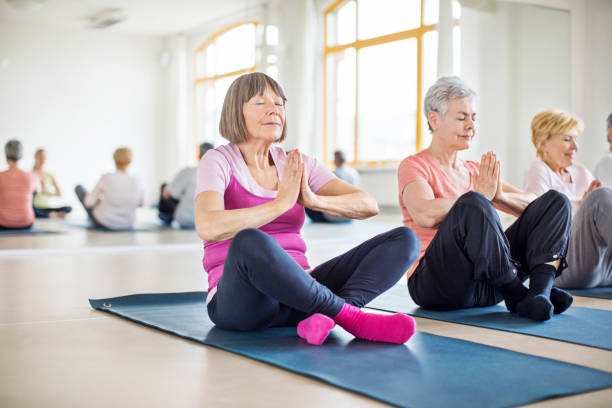 mulheres sênior, meditando na aula de yoga - three people adults germany berlin germany - fotografias e filmes do acervo