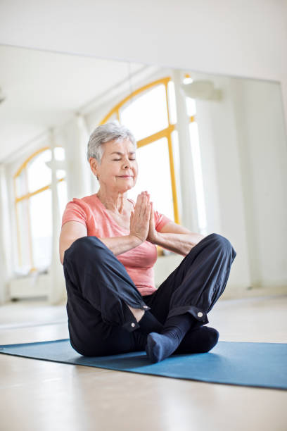 istock Elderly woman with hands clasped doing yoga in gym 666388820