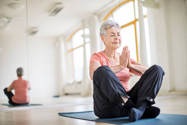 istock Senior woman with hands clasped doing yoga in gym 666388854