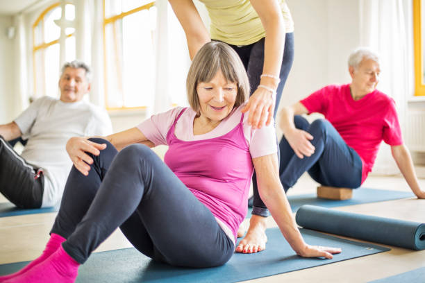 istock Trainer helping senior woman in exercising at gym 666389002