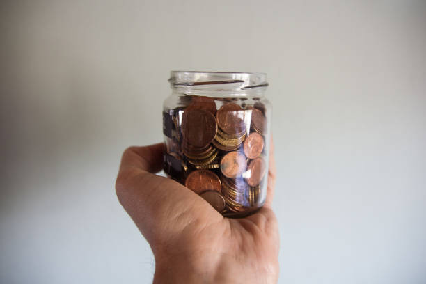istock Hand holding a jar of coins 666390302