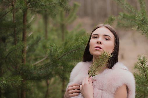 Portrait of a very beautiful girl in a forest dressed in fur.