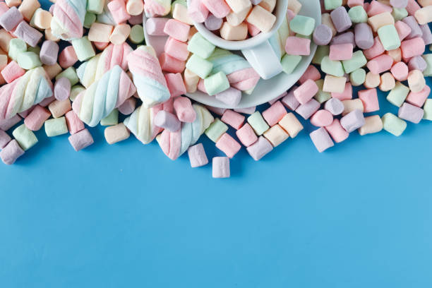 istock Twisted american marshmallow in a white cup on a blue background 666394446