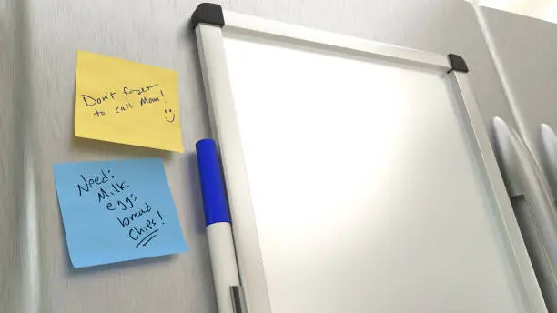 A blank dry erase board on a stainless steel refrigerator.
