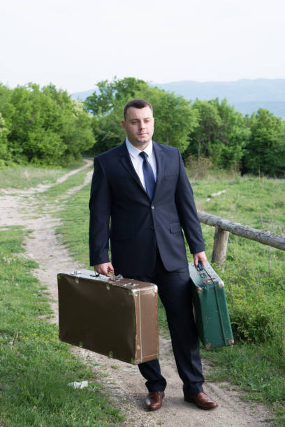 istock Groom with suitcases on a country road 666398044