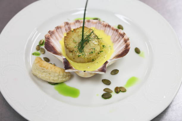 istock Scallop in a shell with grits, pumpkin seeds and saffron sauce. 666479966