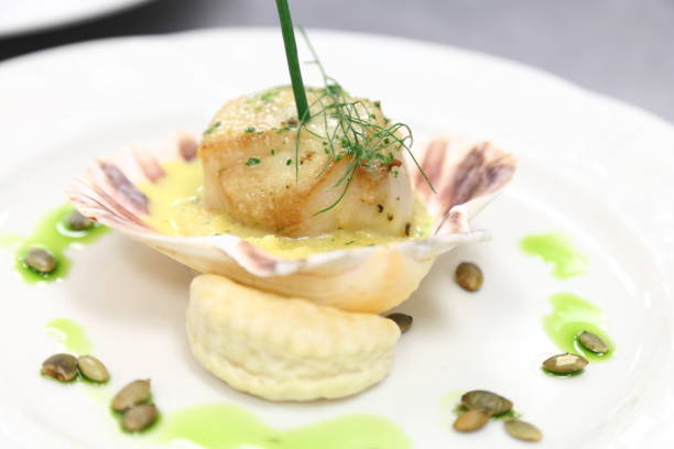 istock Scallop in a shell with grits, pumpkin seeds and saffron sauce. 666479970