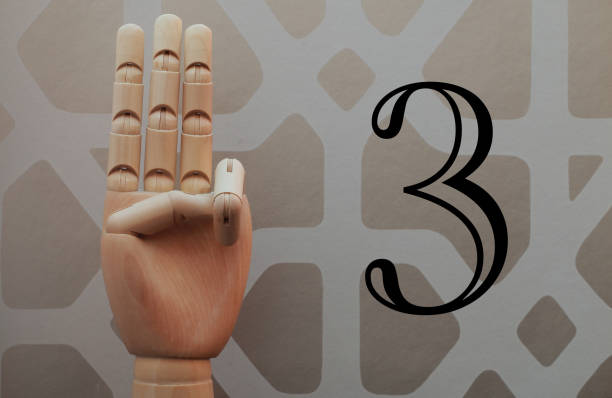 istock Wooden hand with three fingers raised next to number three 666486320