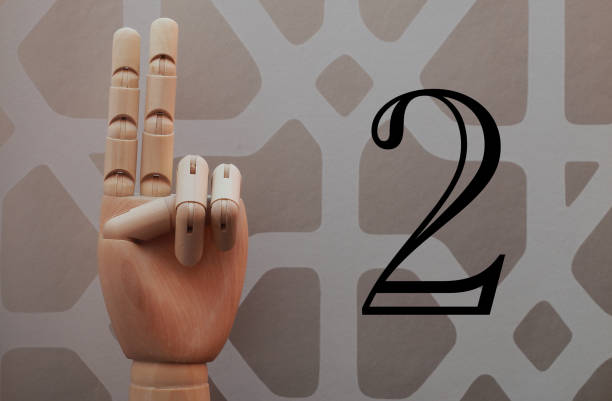 istock Wooden hand with two fingers raised next to number two 666486328