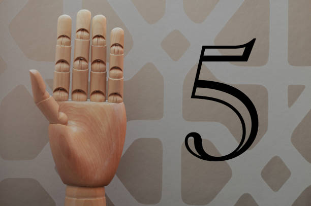 Wooden hand with five fingers raised next to number five