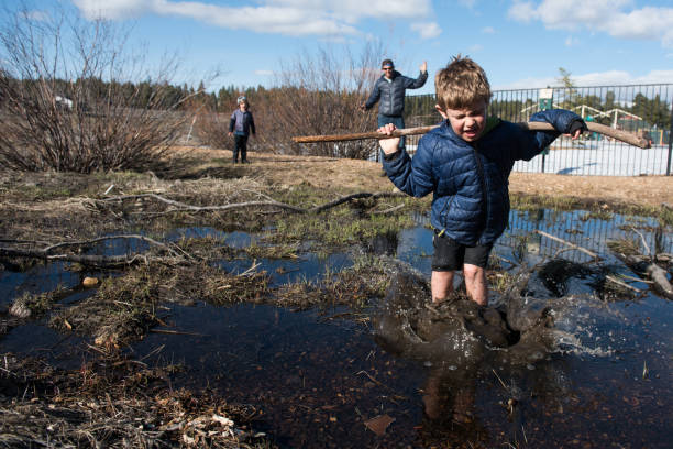 istock Child splashes into muddy pond with dad watching 666493316