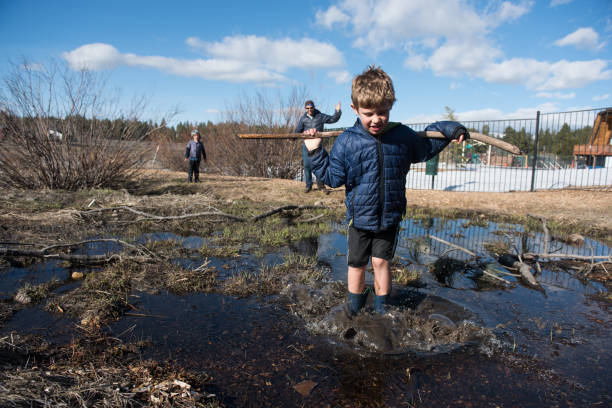 istock Child stands in muddy pond with dad watching 666493318
