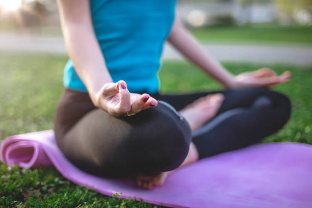 32 years old pretty female doing yoga in park. It is late March and the start of spring. She is doing relaxation exercises to keep inter peace