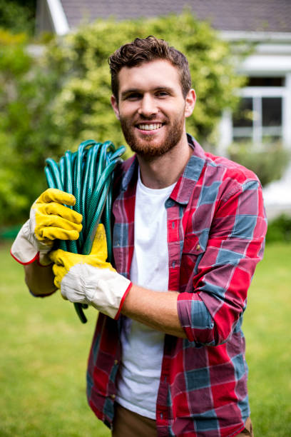 istock Smiling man carrying garden hose in yard 666507208