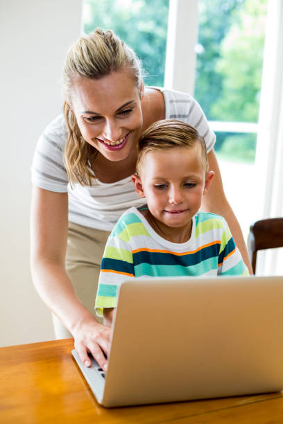 istock Smiling mother and son using laptop at home 666510560
