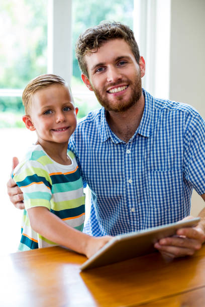 istock Smiling father and son with digital tablet at home 666510704