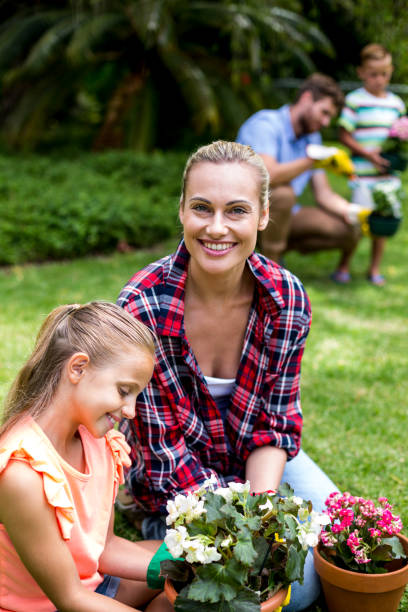 istock Mother helping daughter with flower pots in yard 666513524