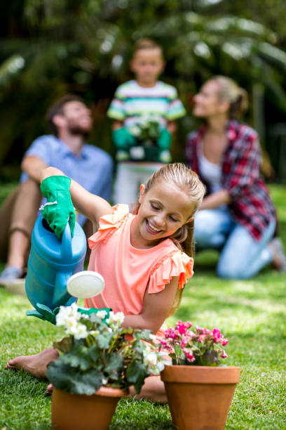 istock Girl watering flower pots in yard 666514342