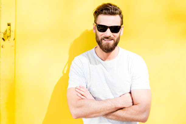 Colorful portrait of a handsome man dressed in white t-shirt on the yellow background