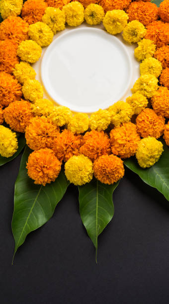 istock flower rangoli made using marigold or zendu flowers and mango leaves over black background with copy space in the middle, selective focus 666521360