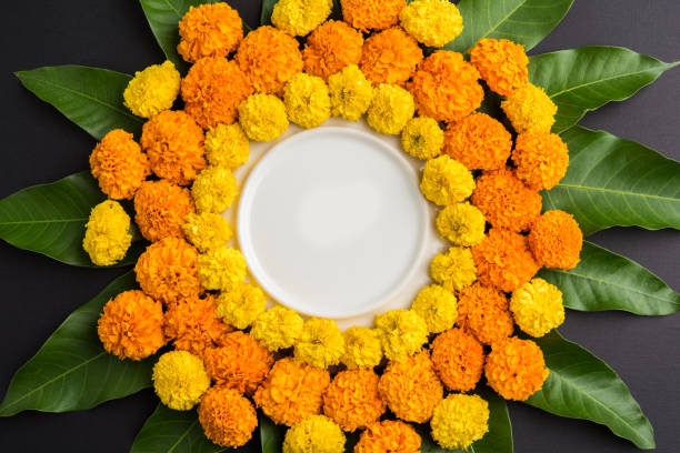 istock flower rangoli made using marigold or zendu flowers and mango leaves over black background with copy space in the middle, selective focus 666523734