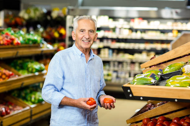 istock Smiling senior man picking out tomatoes 666526804
