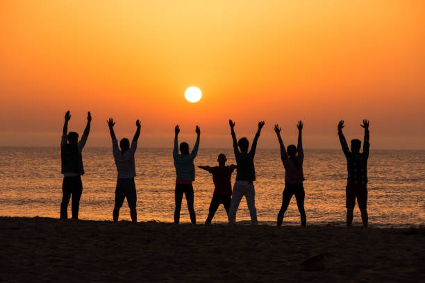 istock Group of people excercising on beach at dawn 666545434