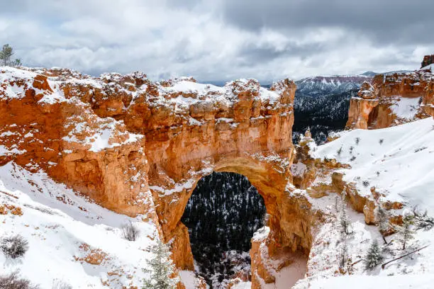 Photo of Natural Arch formation with snow in Bryce Canyon, Utah.