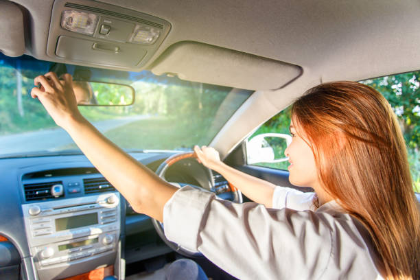 若いアジア女性ドライバーが車の中で彼女のバックミラーを調整します。 - owner women car rear view mirror ストックフォトと画像