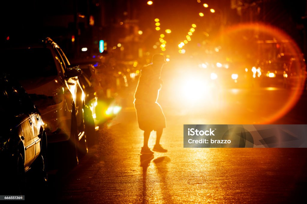 Man crosses busy road at night Man crosses Long Stree, Cape Town, South Africa at night with traffic headlights flaring Pedestrian Stock Photo