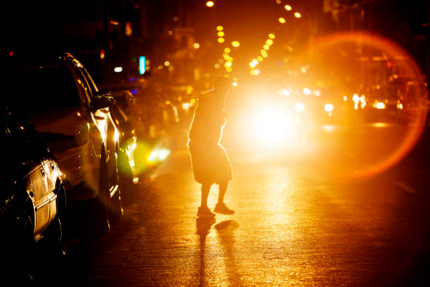 Man crosses busy road at night stock photo