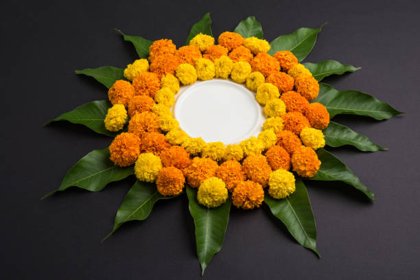 istock flower rangoli made using marigold or zendu flowers and mango leaves over black background with copy space in the middle, selective focus 666556370