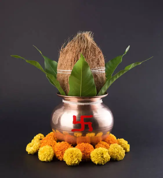 copper kalash with coconut and mango leaf with floral decoration. essential in hindu puja, selective focus, over plain background
